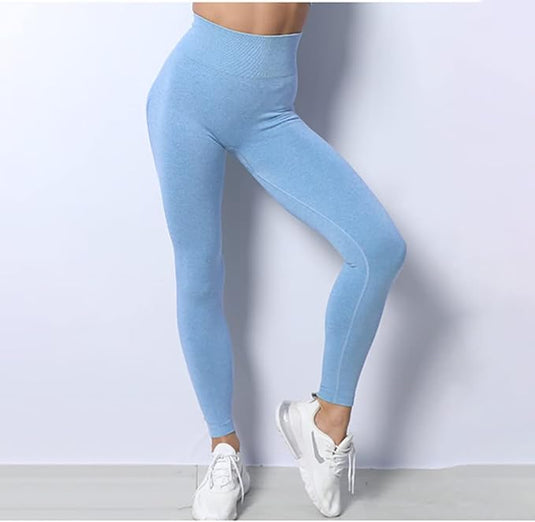 Een vrouw die lichtblauw Zie er geweldig uit en voel je geweldig draagt in deze 3-delige yoga-workoutset en witte sneakers staat tegen een grijze achtergrond, waardoor het zijprofiel van de legging goed zichtbaar is.