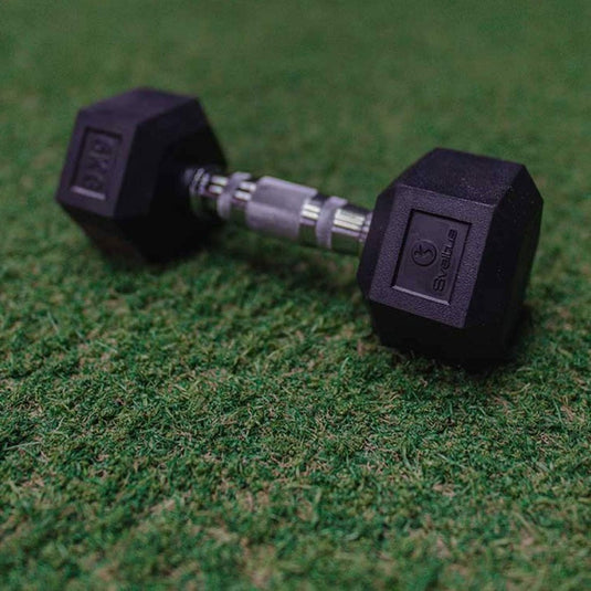 De Ultieme zeshoekige halter van 6 kg staat op groen kunstgras en benadrukt het ergonomische ontwerp en het duurzame rubber voor duurzame prestaties.
