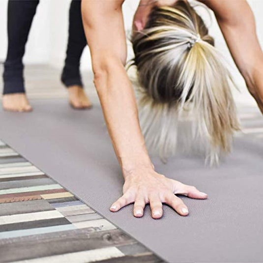Een vrouw die yoga doet op een grijze mat.