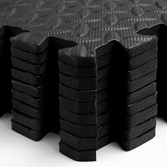 Close-up van zwarte, gestructureerde antislip akoestische puzzelmatten, netjes gestapeld.