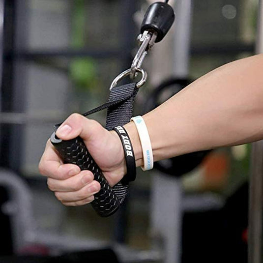 De hand van een persoon houdt een trein vast met de fitness handgrepen kabelgrepen bevestigd aan een kabelmachine, met een polsband ter ondersteuning.