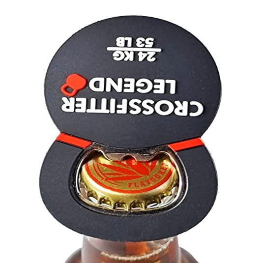 Een zwarte De ultieme combinatie: Bieropener en kettlebell bevestigd aan een flesdop, waarbij de onderkant zichtbaar is met een rood en goud logo, tegen een witte achtergrond.