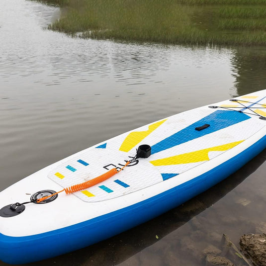 Een kleurrijk stand-up paddleboard met een de veiligste manier om te genieten van het water, aangemeerd aan een met gras begroeide rivieroever.