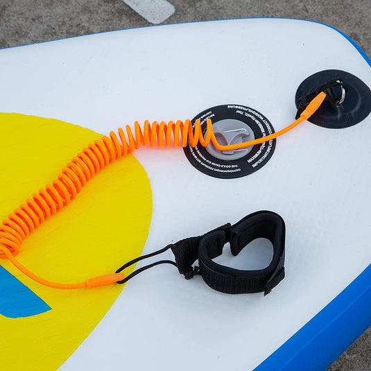 Close-up van een kleurrijk stand-up paddleboard met een de veiligste manier om van het water te genieten en een zwarte enkelband op een grijze ondergrond.