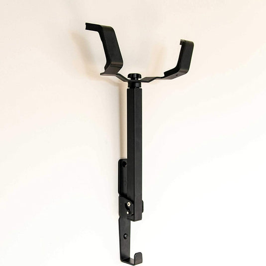 Zwarte wandfietshouder met verstelbaar juk, gemonteerd op een lichtbeige muur met behulp van een ruimtebesparende wandhaak.