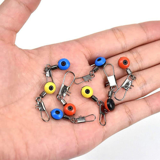Een hand die een verzameling boze oog-amulet-sleutelhangers in verschillende kleuren vasthoudt, beschouwd als De ultieme visaccessoires-set voor elke visser.