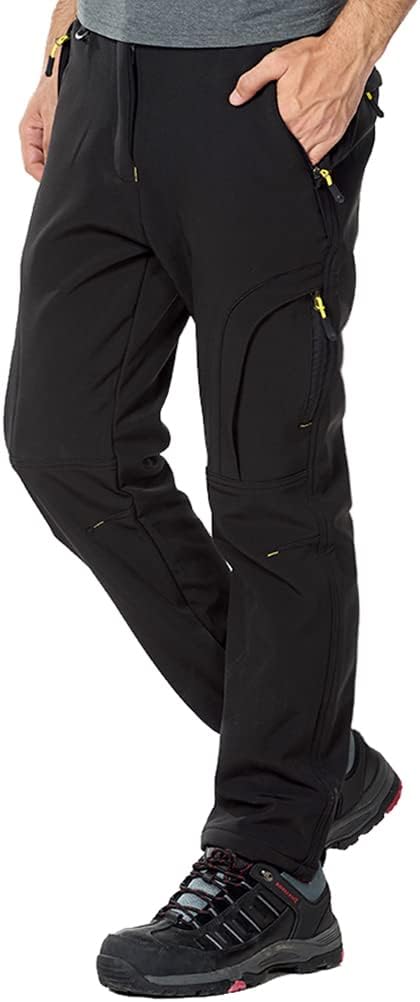 Man in zwarte Houd je warm en comfortabel in de koude met de heren wandel- en skibroek met meerdere zakken met ritssluiting, gecombineerd met zwarte sneakers. Alleen de onderste helft van het lichaam is zichtbaar.