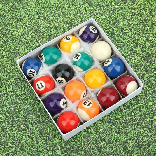 Een set kleurrijke Ontdek duurzame mini hars biljartballen netjes gerangschikt in een witte doos, uitgestald op een groene, grasachtige ondergrond.