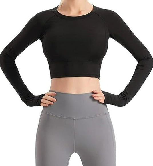 Vrouw, gekleed in een zwarte Naadloze dames fitness crop top en grijze legging met hoge taille, staande met de handen op haar heupen, geïsoleerd op een witte achtergrond.