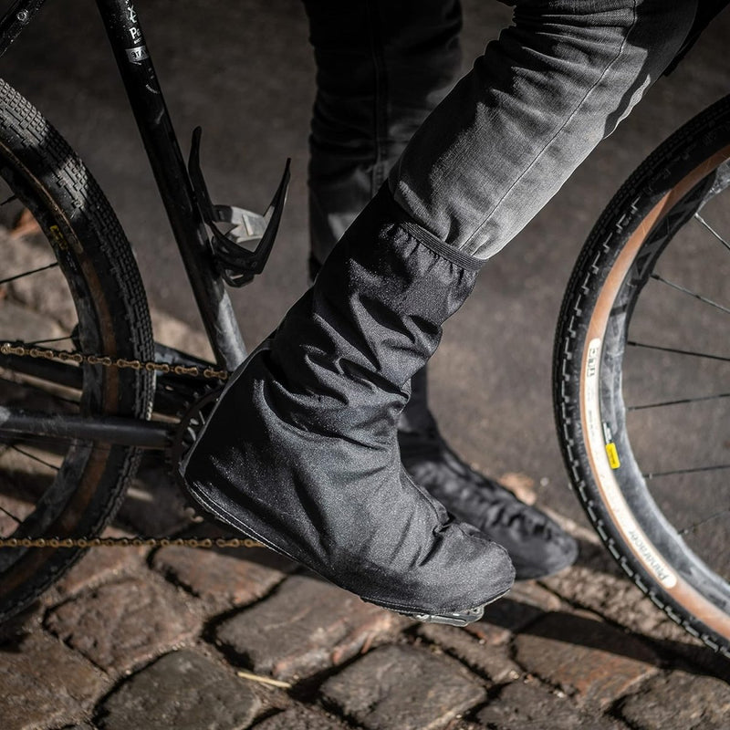 Laad afbeelding in Galerijviewer, Fietser draagt Regenoverschoenen voor fietsers om schoenen te beschermen tijdens het fietsen met waterdichte schoenbeschermers.
