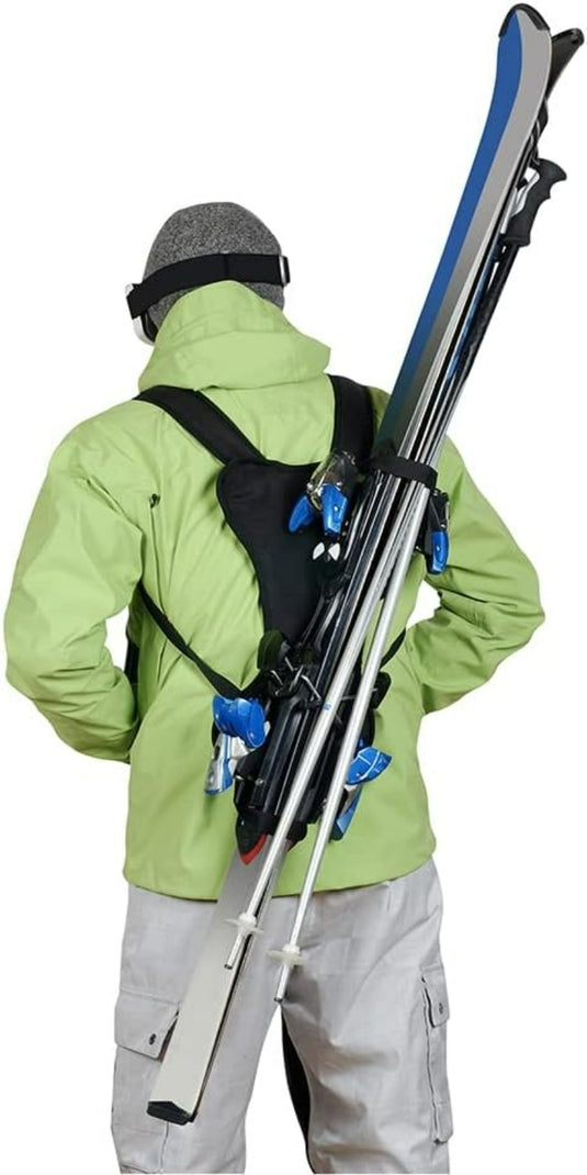 Persoon gekleed in winterkleding en skiback met ski's over zijn schouder.