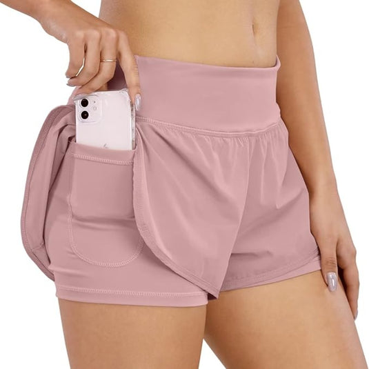 Een persoon die een verlengbare, roze Sportbroek voor dames: comfortabel, krachtig en veelzijdig draagt met een smartphone weggestopt in de zak.