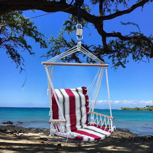Hangende gestreepte stoelschommel onder een boom aan een rustig strand, gemaakt van Snellere, krachtigere en veiligere training met onze bokszakveer.
