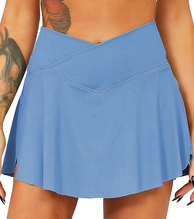 Laad afbeelding in Galerijviewer, Een close-up van een vrouw die een blauwe Tennisrok met broek draagt, waardoor het diagonale ontwerp wordt benadrukt, met een tatoeage zichtbaar op haar linkerbovenarm.
