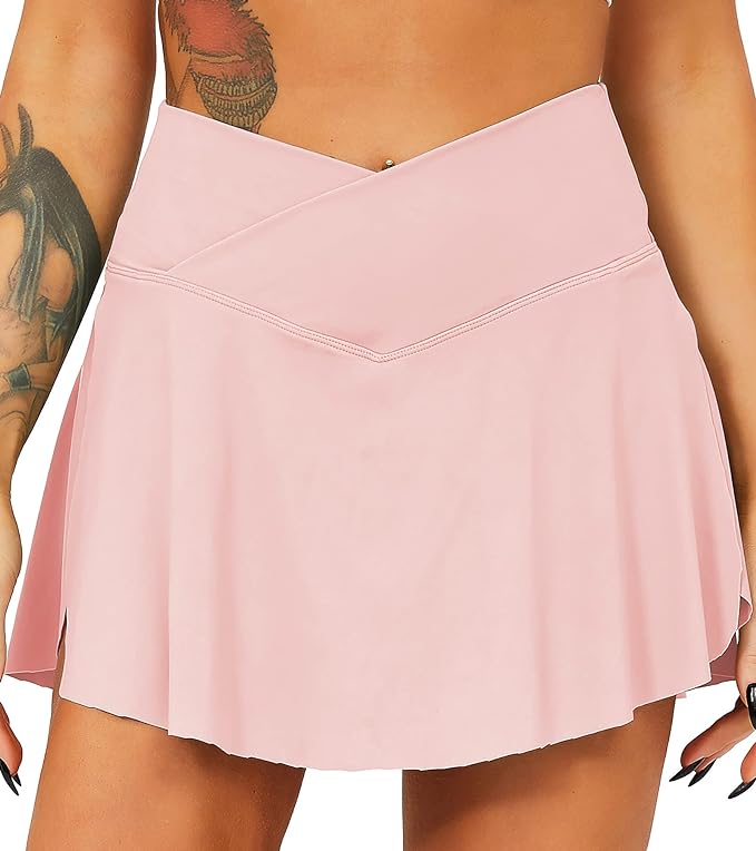 Laad afbeelding in Galerijviewer, Een close-up van een persoon die een roze Tennisrok met broek draagt. Details omvatten een zichtbare tatoeage op de linkerbovenarm.
