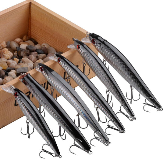 Vang meer vissen met dit Vijf visschubbenlaser-holografie kunstaas voor vissen met driebladige haken, geplaatst op een houten doos gevuld met kleine stenen, in verschillende tinten zwart en zilver.