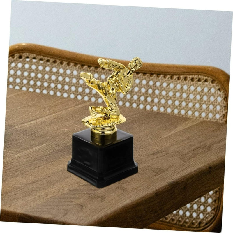 Laad afbeelding in Galerijviewer, Goudkleurige, hoogwaardige Vechtsporttrofee: een schitterende herinnering aan jouw overwinning met een figuur in vechtsporthouding op een houten tafel.
