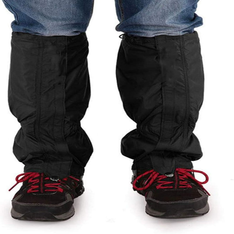 Laad afbeelding in Galerijviewer, Persoon die de ultieme bescherming voor al je buitenactiviteiten in zwart draagt over een spijkerbroek en zwarte wandelschoenen met rode veters, staande met de voeten iets uit elkaar.
