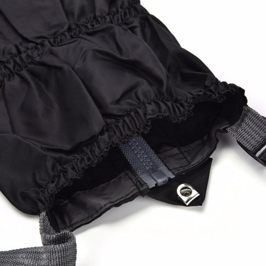 Close-up van een duurzame zwarte beenkappen met elastische banden met ruches, een verstelbare riem met gesp en een metalen lusdetail.