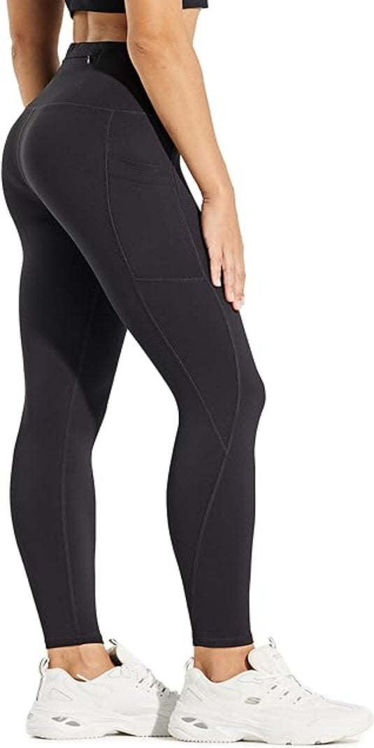 Persoon draagt warme, comfortabele en waterafstotende zwarte thermische leggings en witte sneakers.
