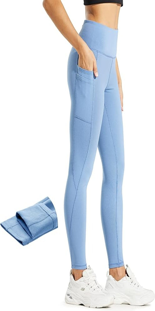Vrouw toont Warm, comfortabel en waterafstotend: de perfecte thermische legging voor dames in het blauw met zakken, gecombineerd met witte sneakers.