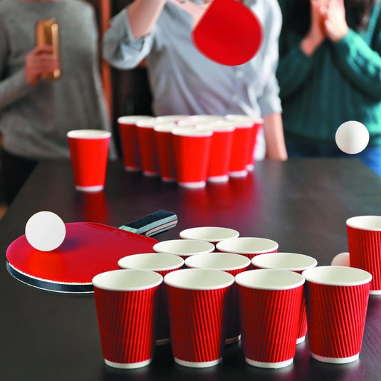 Onder gedimd licht genieten mensen van een levendig spel met rode plastic bekers en de 50 Witte Tafeltennisballen, perfect als feestaccessoires. De spanning stijgt met elke zelfverzekerde peddelslag in deze avond van lachen en competitie.