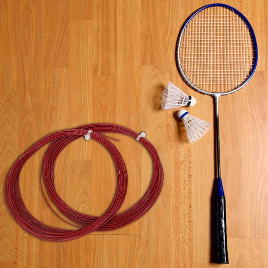 Een badmintonracket en twee shuttles liggen op een houten vloer naast de 10 meter hoge, flexibele multifilament snaren van Keenso, ideaal voor het repareren van rackets.