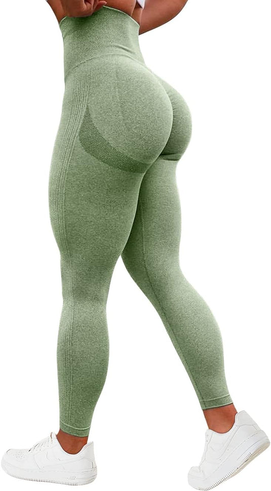 Gekleed in een groene "Ervaar ultiem comfort en stijl met onze compressie sportlegging" met hoge taille, een geplooid billenontwerp en witte sneakers, staat een persoon met de rug naar de camera.