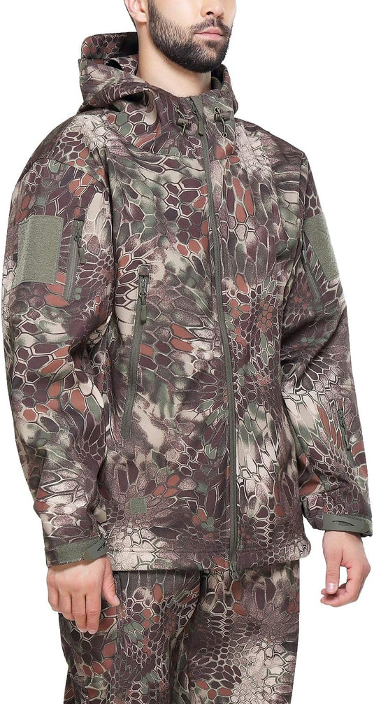 Een man, gekleed in een Camouflage tactische heren softshell jas met meerdere zakken en capuchon, staande tegen een effen achtergrond.