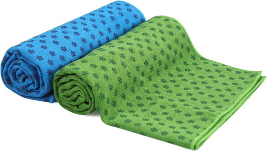 Twee opgerolde yogahanddoeken, een blauwe en een groene met donkere patronen, rusten op een witte achtergrond. Deze antislip yogahanddoeken zijn stijlvol en sneldrogend voor jouw gemak tijdens het oefenen. Verbeter je ervaring met Verbeter je yoga-ervaring met antislip sneldrogende yogahanddoeken!.