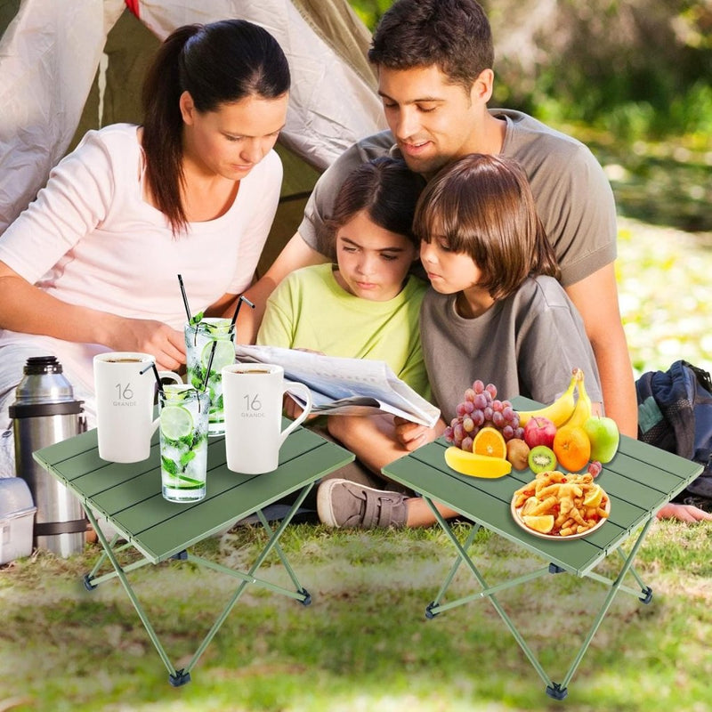 Load image into Gallery viewer, Een gezin ontspant zich buiten hun tent, verdiept in boeken. Twee compacte Ontdek de ultieme kampeerervaring met onze draagbare campingtafel! Op tafels staan drankjes, een fruitschaal en een snackschotel.
