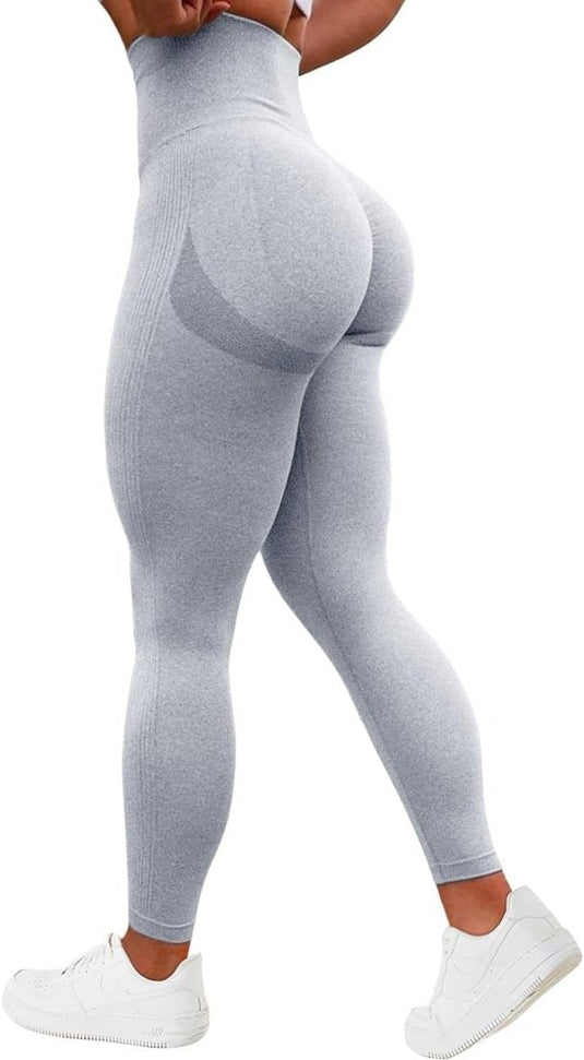 Een persoon in een grijze legging met hoge taille, een geplooid billenontwerp en witte sneakers, van achteren gezien, draagt de Ervaar ultiem comfort en stijl met onze compressie sportlegging!.