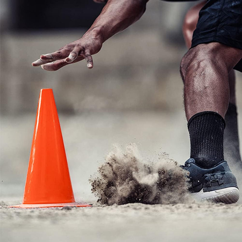 Laad afbeelding in Galerijviewer, Een atleet in sneakers en zwarte sokken rent langs een trainingskegel en doet stof opwaaien tijdens de voetbaltraining met onze premium trainingskegels.
