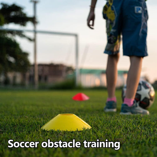 Een kind in sportkleding staat bij een voetbal en een gele kegel op het gras, met meer kegels in de verte. In de buurt, een coördinatieladder van de "Verbeter je spel met deze complete voetbaltrainingsaccessoireset" suggereert een nadruk op behendigheid tijdens de training.