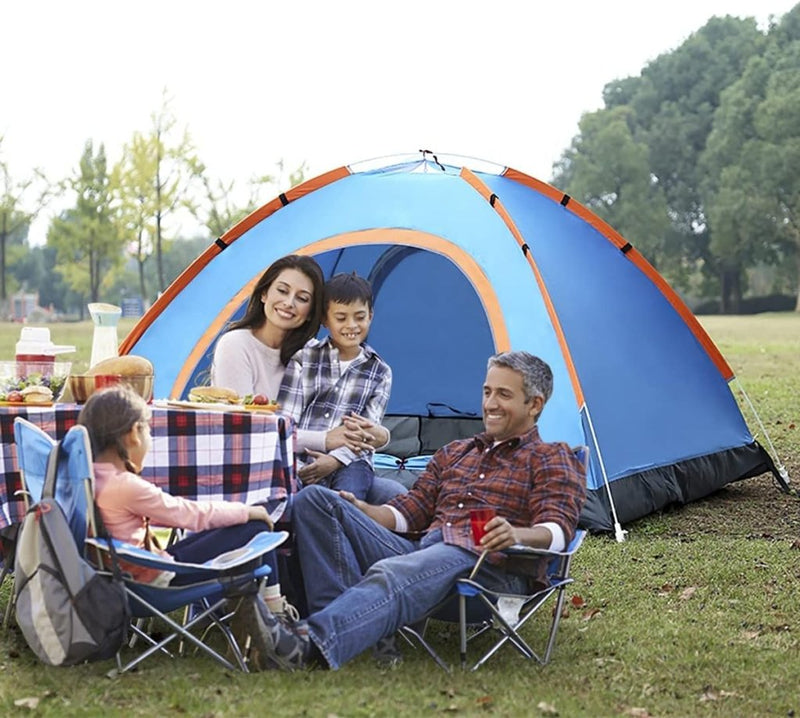 Laad afbeelding in Galerijviewer, Een gezin van vier geniet van het buitenleven, verzameld rond een picknicktafel naast hun ultralichte, draagbare blauwe Ontsnap naar de natuur tent voor twee. Omringd door de natuur met eten en drinken, genieten ze van het moment in hun waterdichte, winddichte schuilplaats genesteld tussen de bomen.
