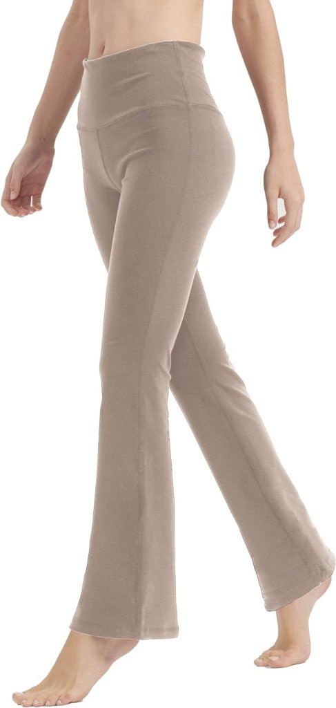 Een persoon staat blootsvoets tegen een witte achtergrond en draagt de Yoga broek voor vrouwen: Perfecte buikcontrole en comfort in beige.