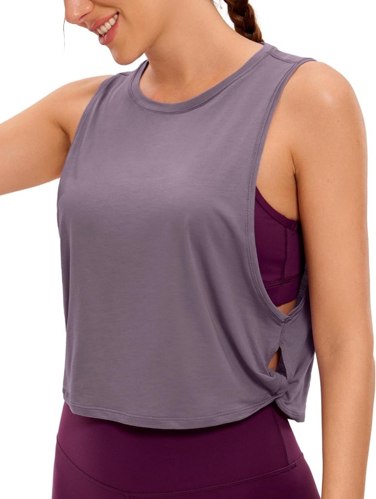 Load image into Gallery viewer, Een persoon draagt een mouwloos grijs topje over een paarse sportbeha met uitsparingen aan de zijkanten. De Yoga Dames Pima Cotton Workout Tank Crop combineert stijl en comfort, perfect voor elke workoutroutine.
