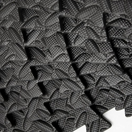 Een close-up van een zwarte mat met een patroon erop, die vloerbeschermingspuzzelmatten biedt voor fitnessapparaten.