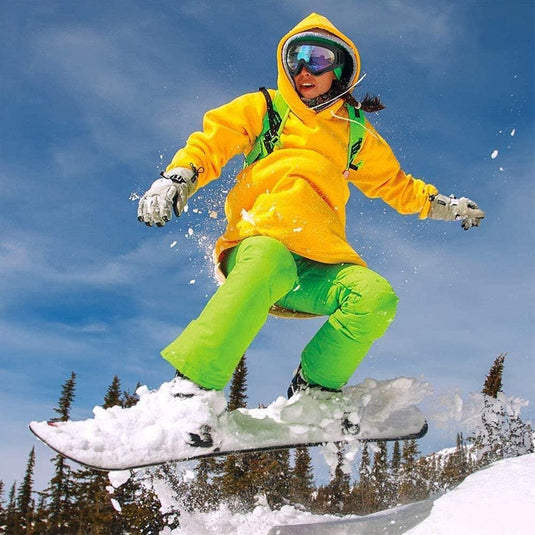 Een persoon die snowboardt in een gele jas en gele broek, uitgerust met de Bescherm je ogen en geniet van de wintersport met deze hoogwaardige sneeuwbril om te beschermen tegen wind.