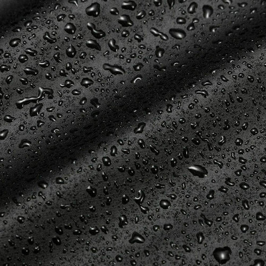 Close-up van waterdruppels op een zwart, gestructureerd oppervlak, waardoor een glanzende en gedetailleerde Bescherm je roeimachine tegen weersinvloeden ontstaat met deze waterdichte roeimachinehoes look.
