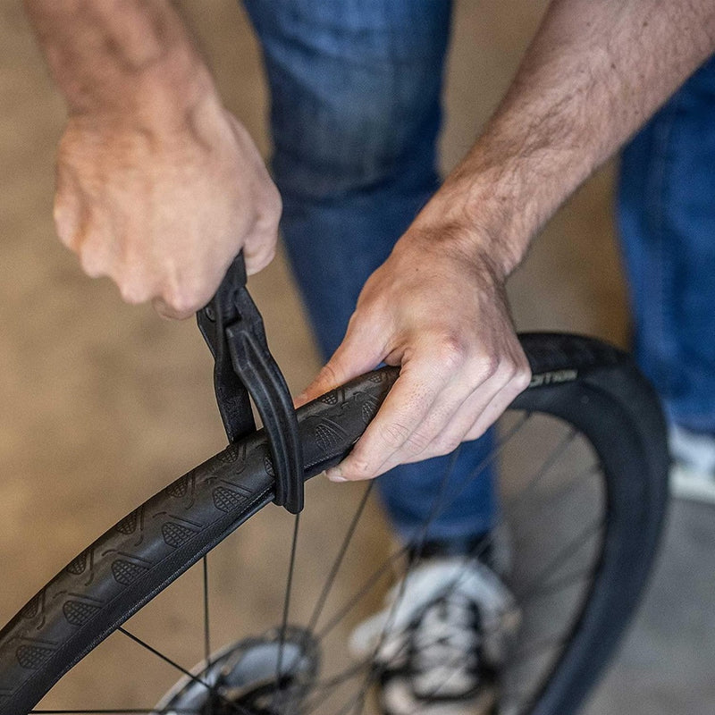 Laad afbeelding in Galerijviewer, Een man gebruikt een Maak het wisselen van banden eenvoudig met onze bandentang voor fietsen! om een band op een fiets te zetten.
