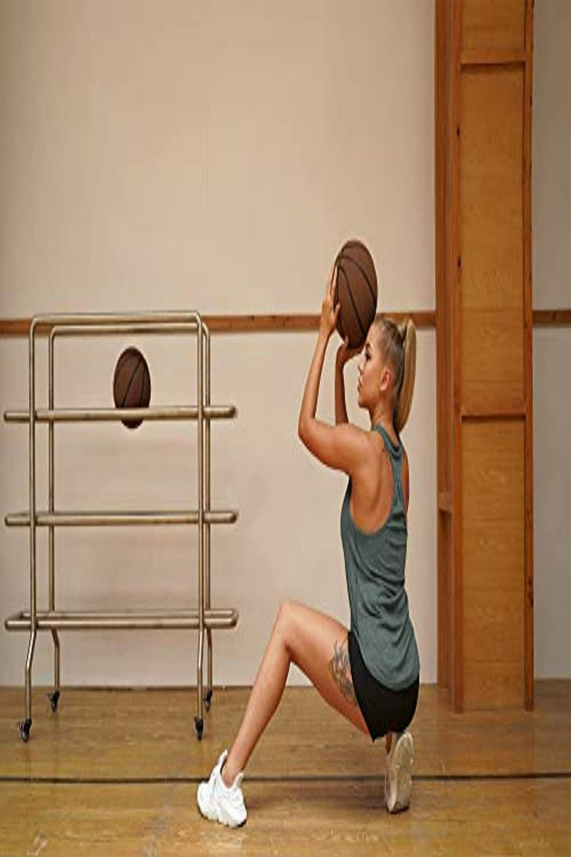 Laad afbeelding in Galerijviewer, Een vrouw in een sportschool die zich voorbereidt op het schieten van een basketbal, gekleed in de Ontdek de stijlvolle en functionele dames tanktop sporttop racerback voor maximale bewegingsvrijheid, met een ballenrek op de achtergrond.
