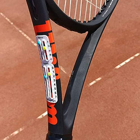 Een close-up van een Draagbaar tennisscorebord op een tennisbaan met een tennisracket op de achtergrond.