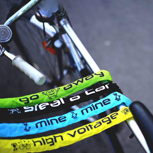 Close-up van een fietsstuur met kleurrijke tapes met patronen eromheen gewikkeld, inclusief teksten als 'go green', 'high voltage' en 'mine', beveiligd door een Kettingslot: de ultieme bescherming voor je fiets.