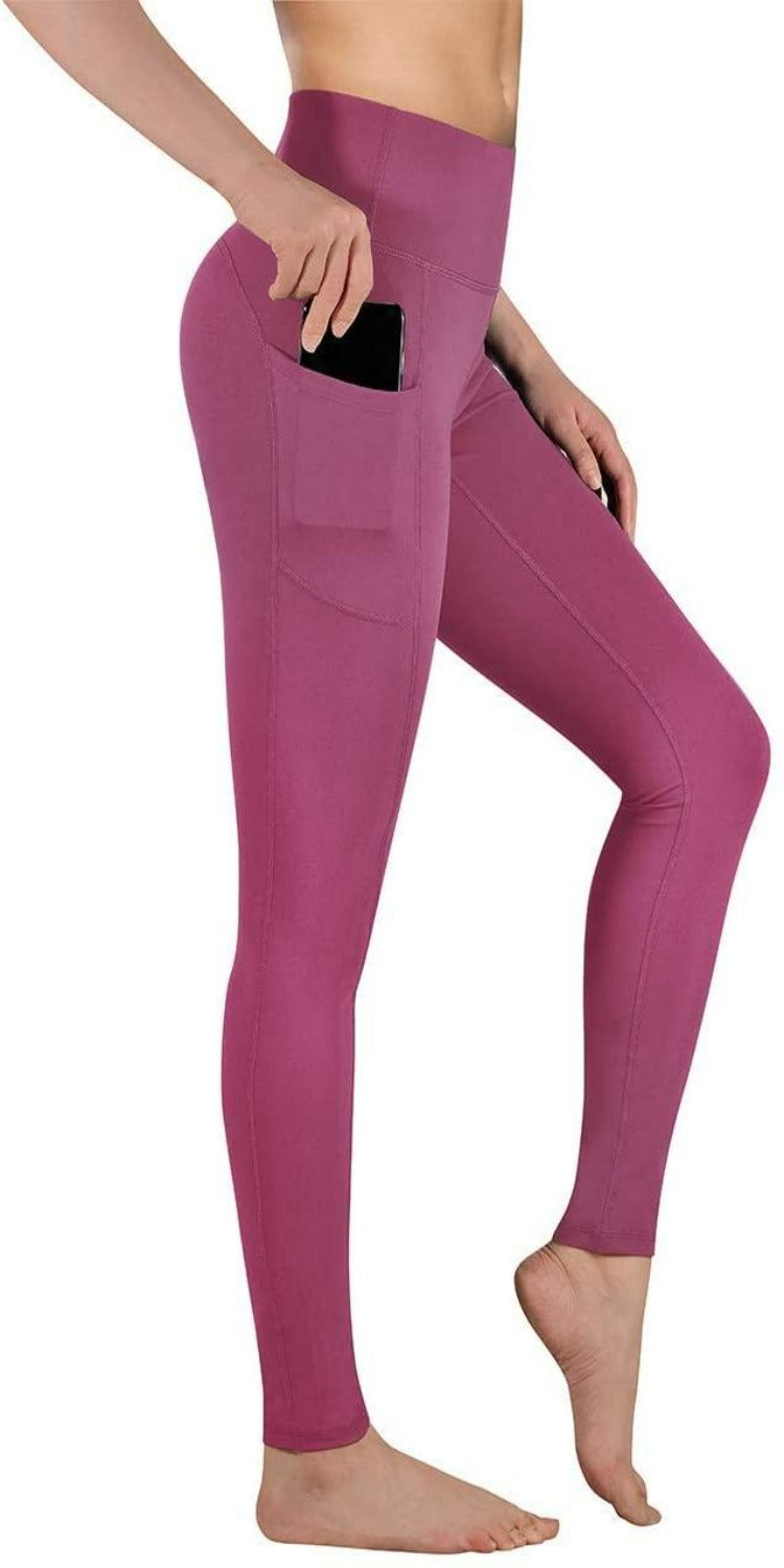 Laad afbeelding in Galerijviewer, Vrouw, gekleed in roze hoge taille legging dames met een zijzak, staande op één been, wat de pasvorm en het ontwerp van de legging laat zien.
