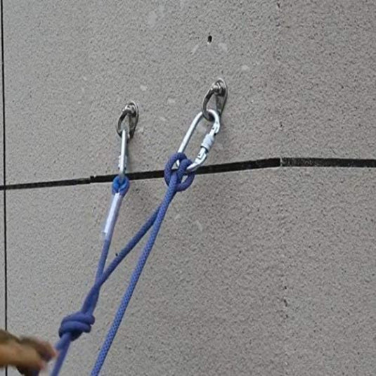 Een man gebruikt Veilige ankerpunten met ophangplaten om een touw veilig aan een permanent Betrouwbaarheidsankerpunt aan de muur te bevestigen, waardoor veilige buitenplezieractiviteiten worden gegarandeerd.