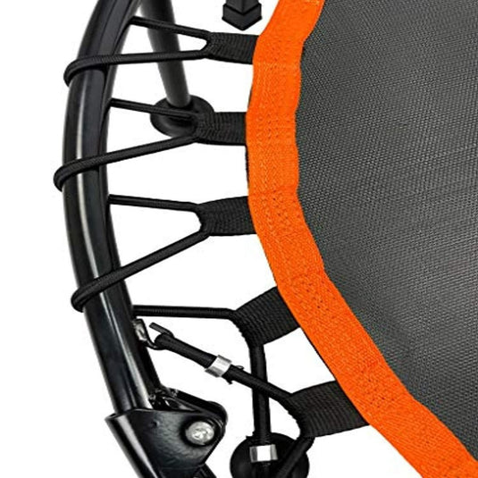 Close-up van een zwart-oranje mini-fitness-trampoline voor cardio en gedronken met metalen veren en frame.