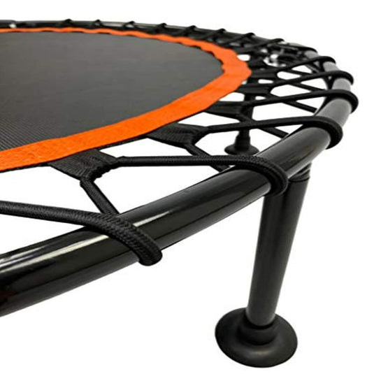 Close-up van een mini-fitnesstrampoline voor cardio en hoofdpijn met een zwart springoppervlak en oranje rand op een witte achtergrond.