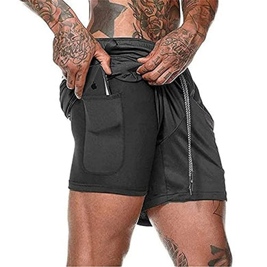 Een man met getatoeëerde armen in het zwart Ontdek het ultieme comfort en de functionaliteit van onze heren 2-in-1 shorts, terwijl hij met beide handen aan de tailleband trekt.