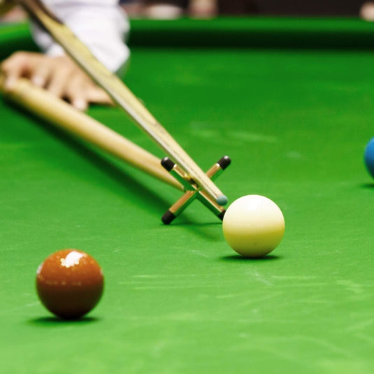 Een man speelt snooker op een groene tafel met Snooker tafelsteunen: verbetering je spel met precisie en stabiliteit met deze keubruggen.